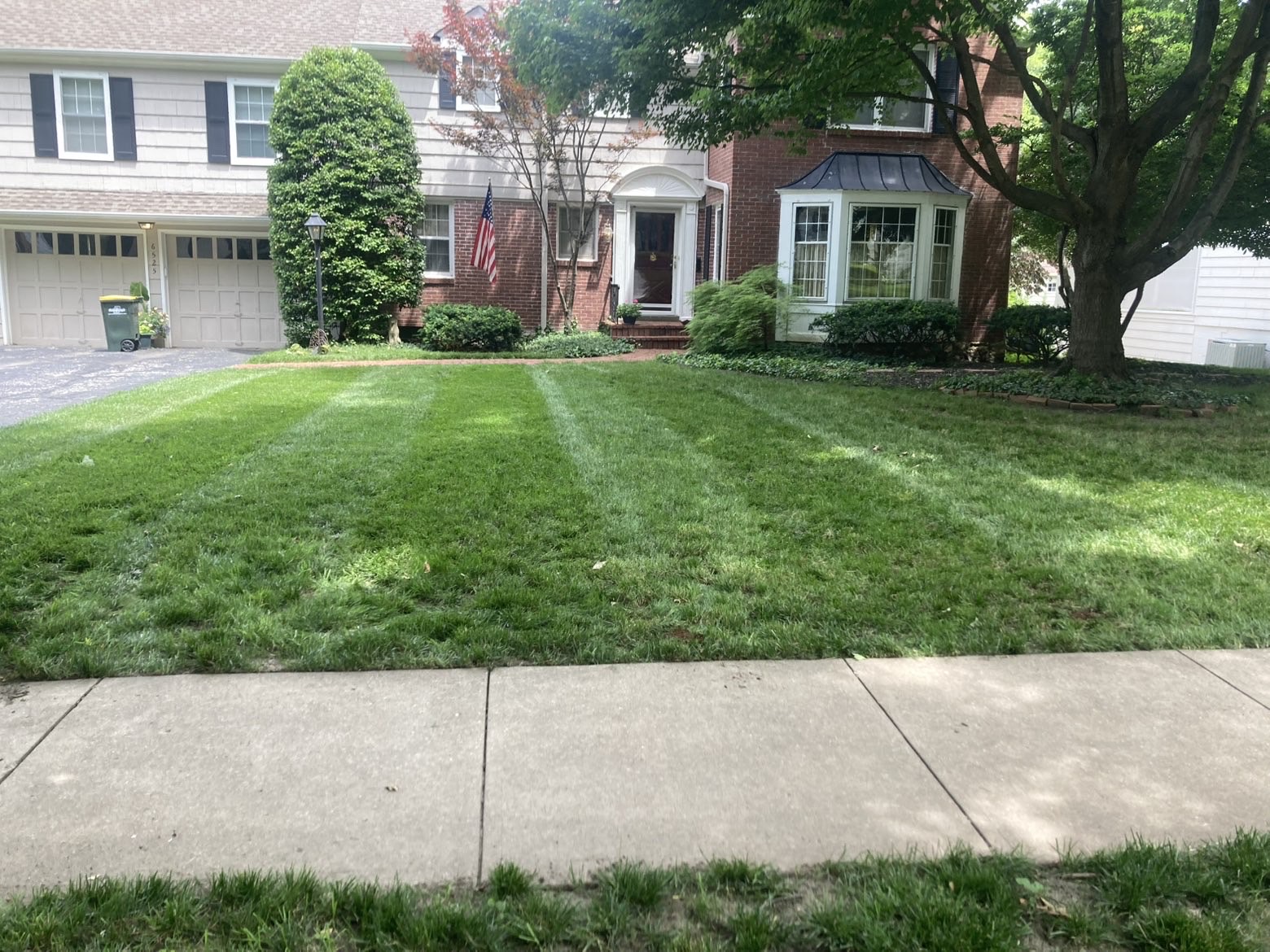 Striped front lawn of a brick colonial home